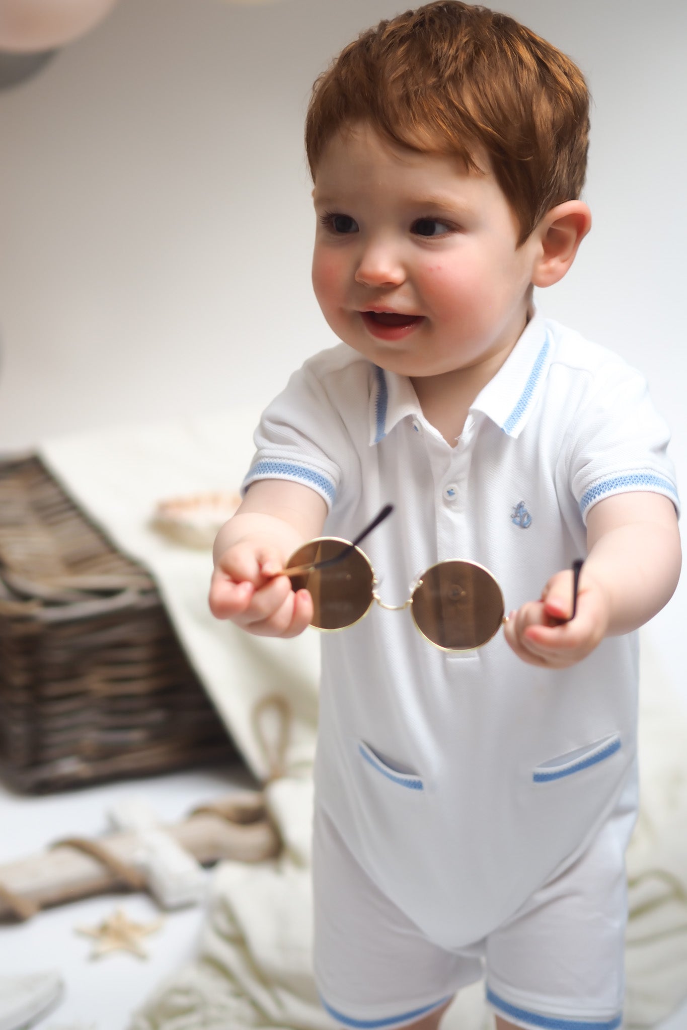 baby boy in romper holding sunglasses